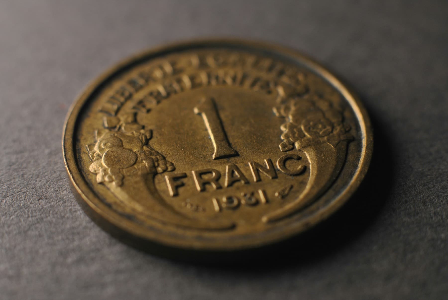 Une pièce de un franc posée sur une surface sombre