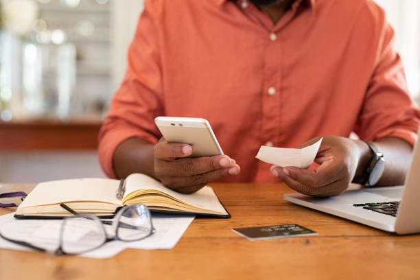 Un parent tient un reçu papier d’une main et son téléphone de l’autre